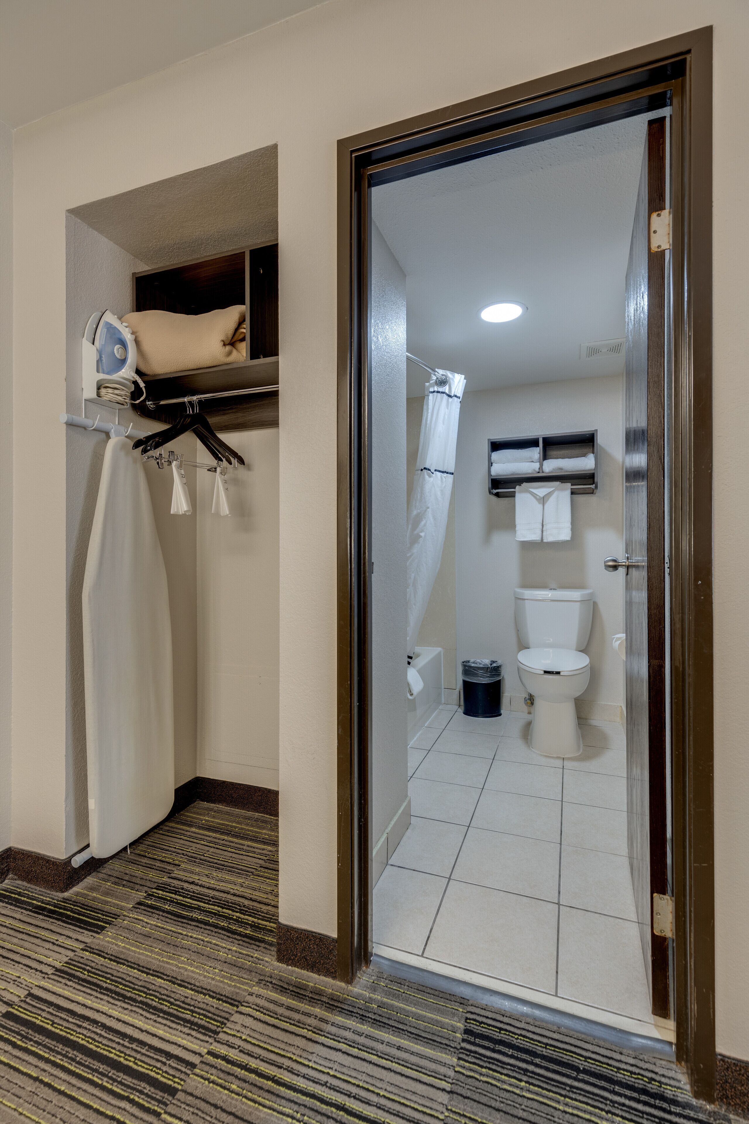 A bathroom with a toilet, a shower curtain, and a towel rack.