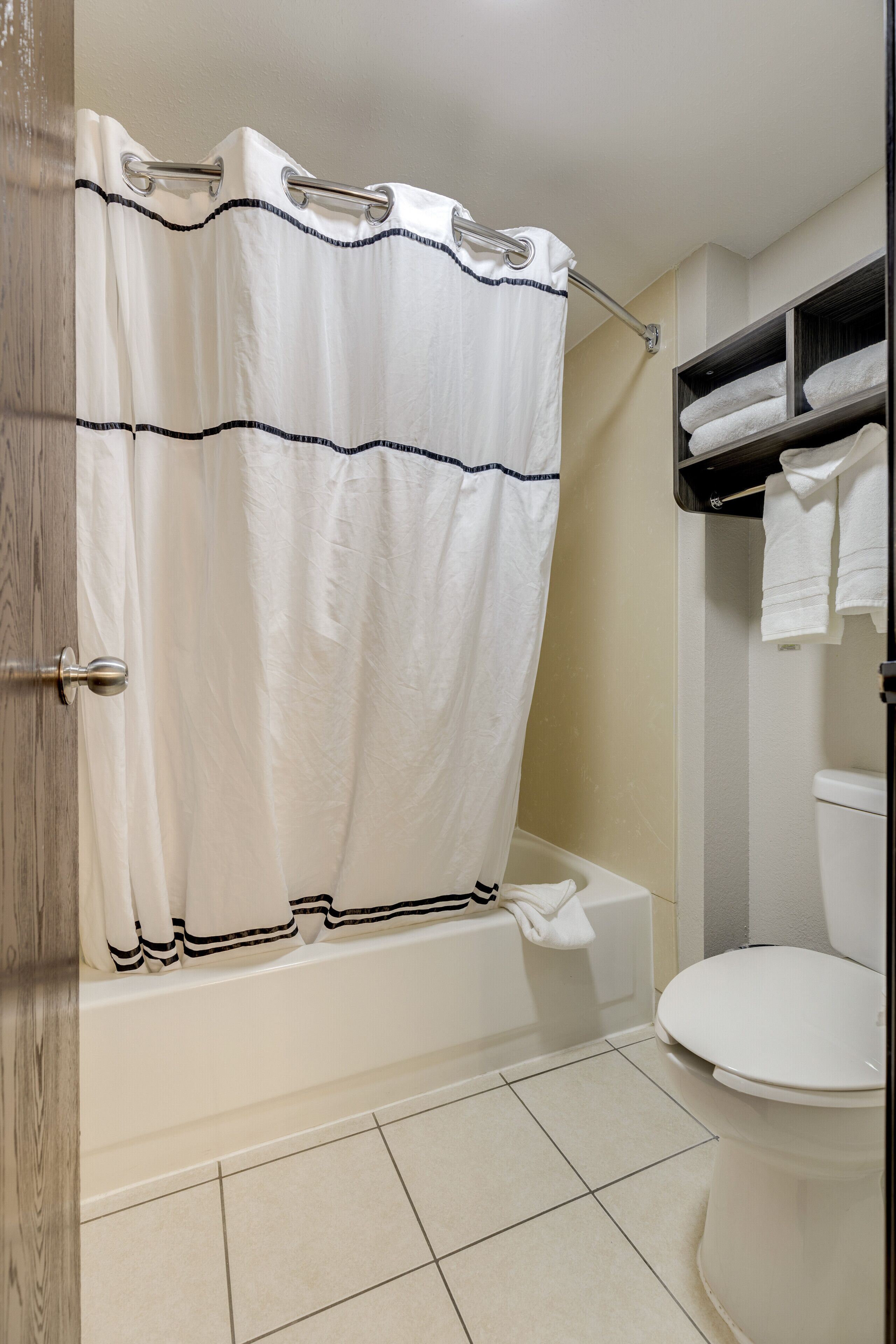 A bathroom with a bathtub, toilet, and a towel rack with towels.