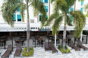 A hotel exterior with outdoor seating, palm trees, and a sign for 'K Bistro'. - Magnuson Grand Hotel Maingate West (Kissimmee)