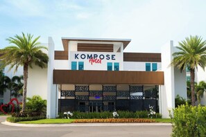 A modern hotel named KOMPOSE with a white facade, blue accents, and a decorative facade. - Magnuson Grand Hotel Maingate West (Kissimmee)