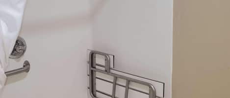 Un bagno con una vasca da bagno bianca, una maniglia di metallo e un porta asciugamani.