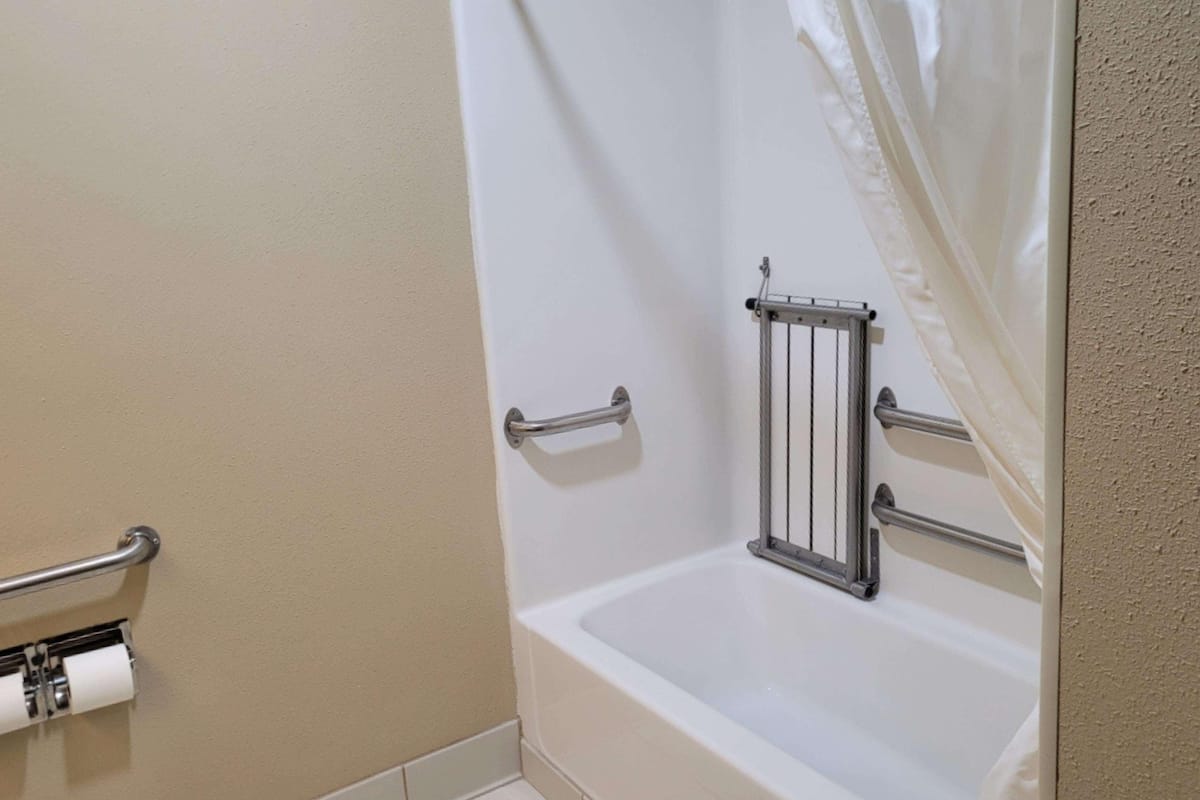 A bathroom with a bathtub, a shower curtain, and a towel rack.