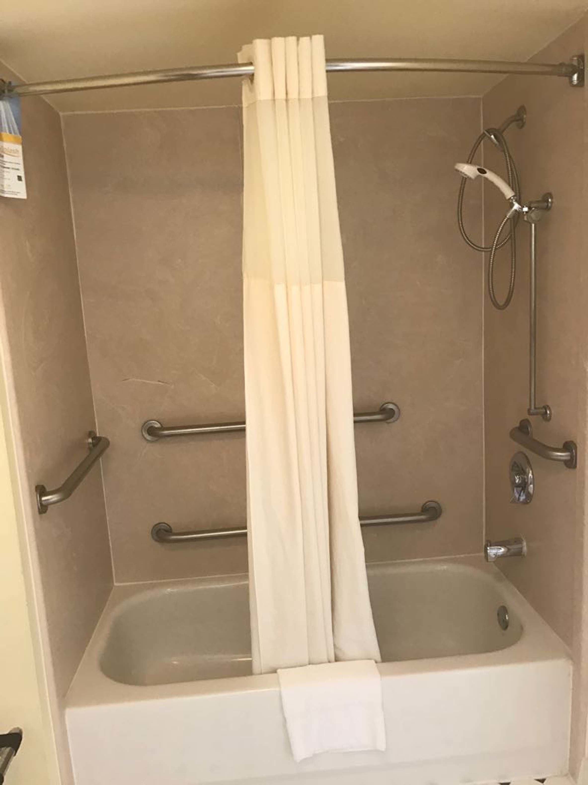 A bathroom with a bathtub, a shower, and grab bars.