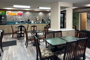 A restaurant with wooden chairs and tables, a counter with a menu, and a tiled backsplash.