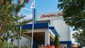 Un hôtel Hampton Inn au design moderne, doté d’une entrée imposante et d’un espace extérieur aménagé pour se détendre.