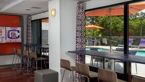 Un bar moderne avec des tabourets hauts et une vue sur la piscine.