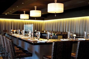 A bar area with a long counter, multiple seating arrangements, and pendant lighting. - Hotel Sepia (Québec City)