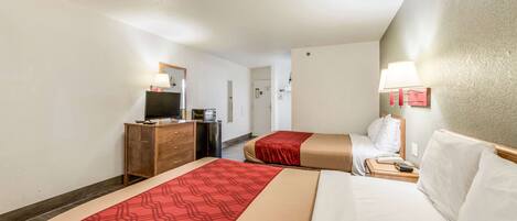 Una habitación de hotel con dos camas, un aparador, un televisor y una lámpara.