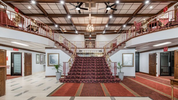 A grand staircase with a red carpet leading to a balcony with ornate railings. - Econo Lodge Truman Inn (Sedalia)