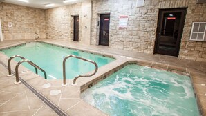 A swimming pool with a stone wall and a hot tub. - Econo Lodge Truman Inn (Sedalia)