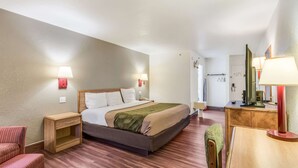 A hotel room with a bed, bedside tables, a chair, a desk, and a mirror. - Econo Lodge Truman Inn (Sedalia)