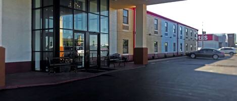A building with large glass windows, a covered entrance, and a parking lot.