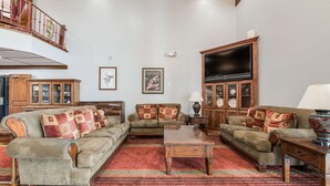A spacious living room with a high ceiling, a large flat-screen TV, and a red patterned carpet. - Econo Lodge Truman Inn (Sedalia)