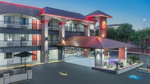 A hotel with a central courtyard, multiple balconies, and a prominent entrance with a red-lit canopy. - Super 8 by Wyndham Austin University/Downtown Area (Austin)