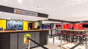 A Super 8 University Downtown hotel lobby with a reception desk, seating area, and a large screen displaying a welcome message. - Super 8 by Wyndham Austin University/Downtown Area (Austin)