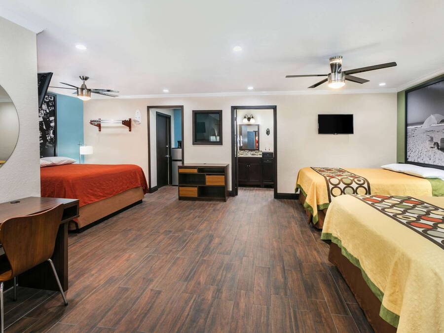 Habitación de hotel con dos camas, un escritorio, una silla, un televisor y un ventilador de techo.
