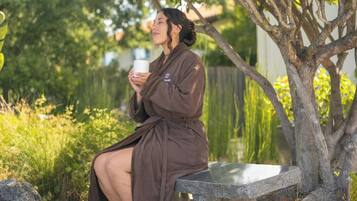 A person sitting on a stone bench outdoors, holding a white mug.