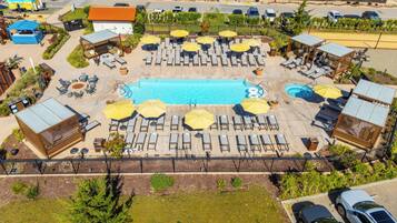 A rooftop pool area with multiple sun loungers and umbrellas, surrounded by a fence and various buildings.