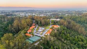 An aerial view of a residential area with houses, a tennis court, and a swimming pool.