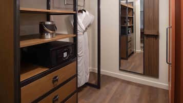 A hotel room with a wooden wardrobe, a mirror, a robe, and a minibar.