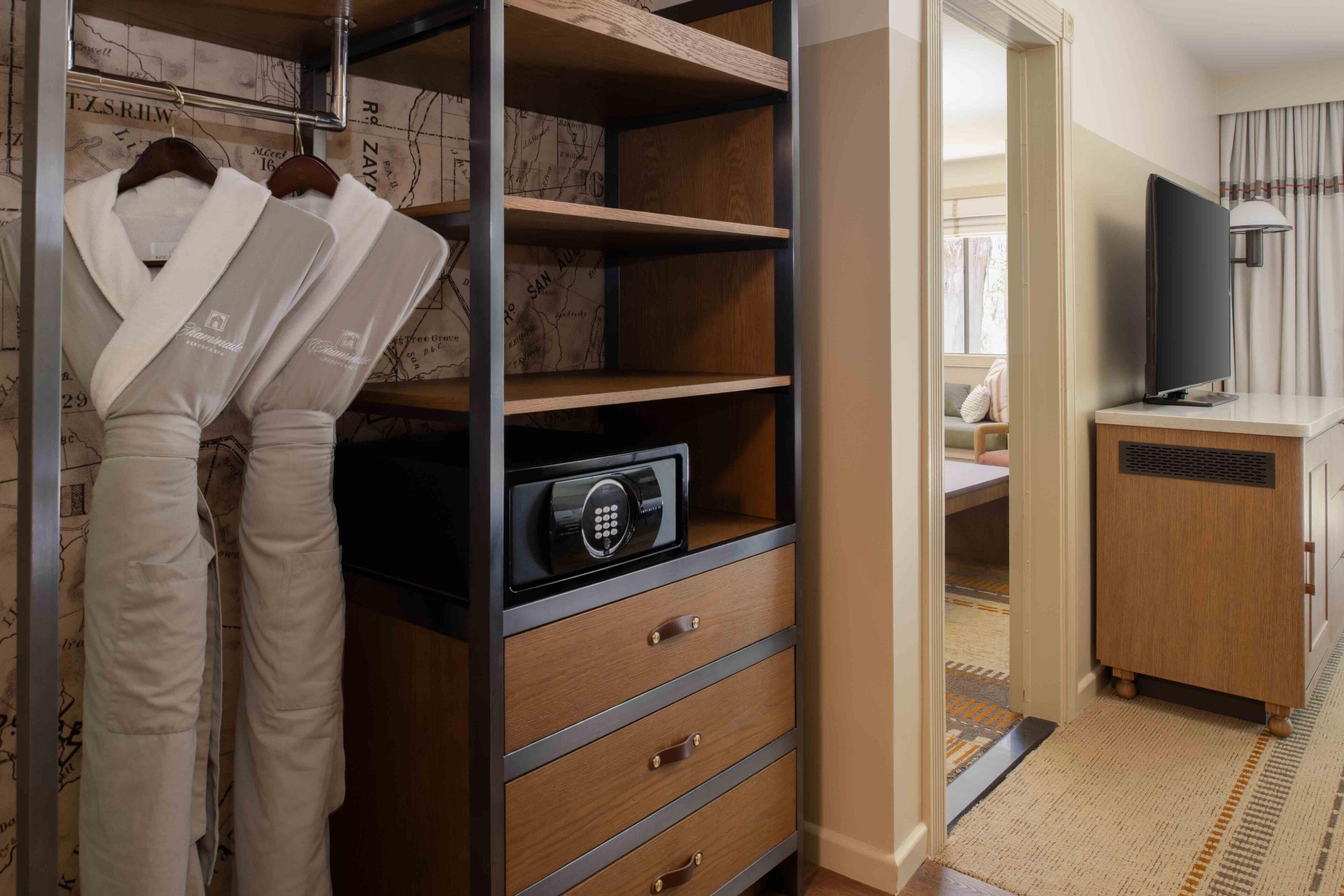 Um closet espaçoso com prateleiras de madeira, um cofre e cabides.