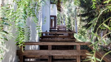 A wooden staircase leading to a white building surrounded by greenery.