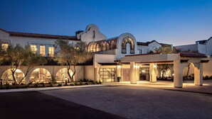 A modern hotel with a Mediterranean architectural style, featuring arched windows and a covered entrance area. - Chaminade Resort & Spa (Santa Cruz)