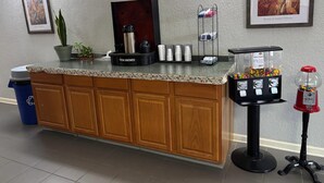 Un área de recepción con mostrador, máquina de café, cubo de basura y máquina expendedora de golosinas.
