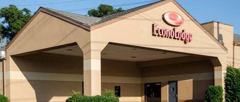 Un hotel con entrada techada, estacionamiento y un letrero que dice "EconoLodge".