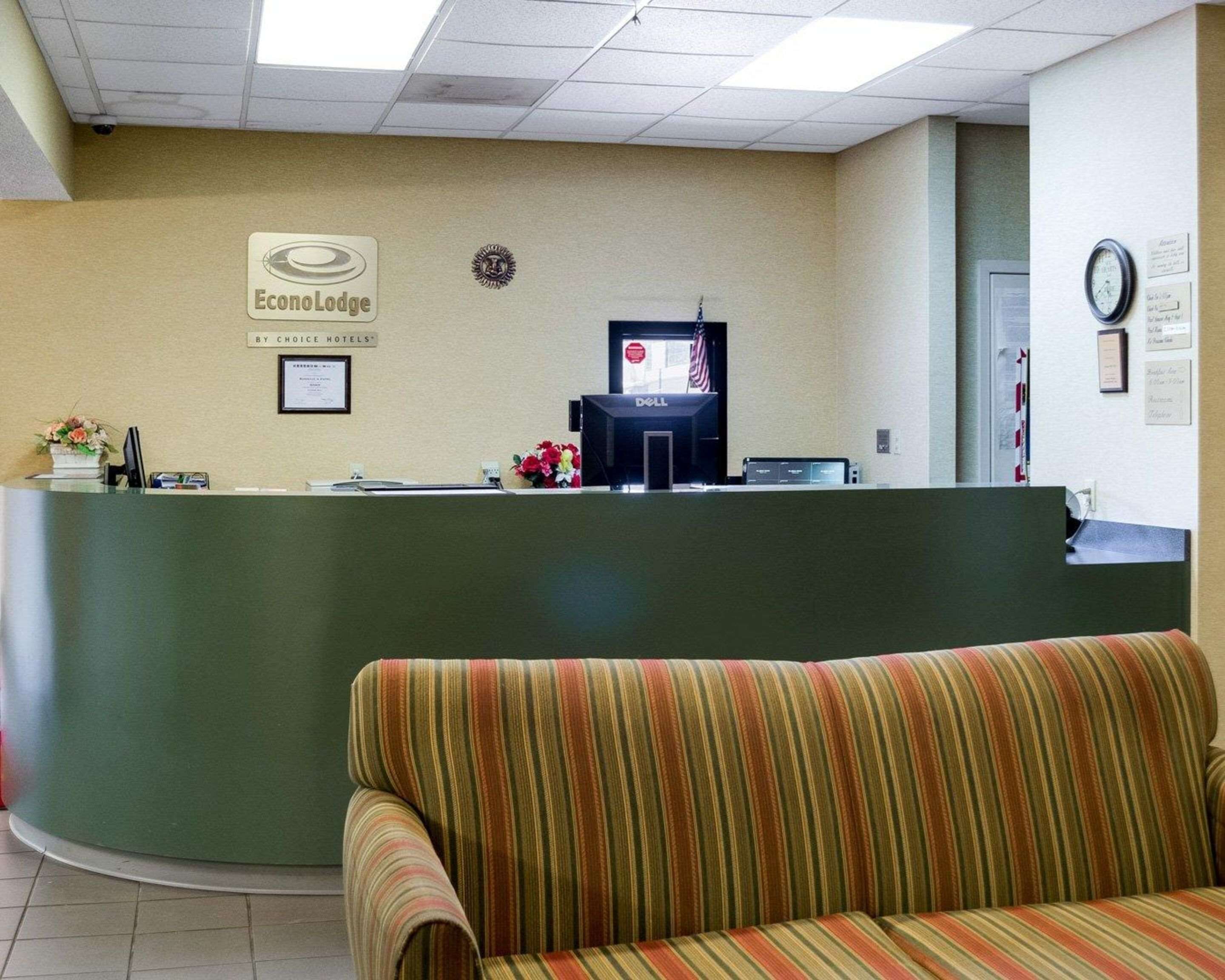 A reception area with a green reception desk, a framed certificate on the wall, and a striped sofa in the foreground.