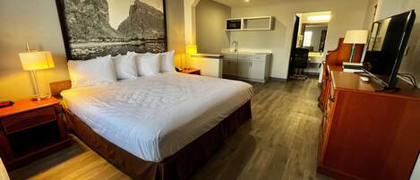 Habitación de hotel con una cama grande, un escritorio, un televisor y una kitchenette.