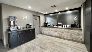 Un área de cocina moderna con estación de café, microondas y refrigerador.