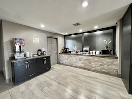 Un área de cocina moderna con estación de café, microondas y refrigerador.