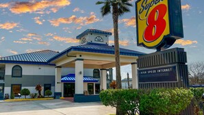 Un hotel con un llamativo letrero de 'Super 8', una entrada cubierta y un letrero que indica 'Internet de alta velocidad'.