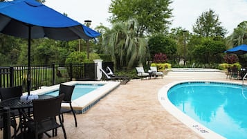 A pool area with lounge chairs, umbrellas, and a tiled deck.