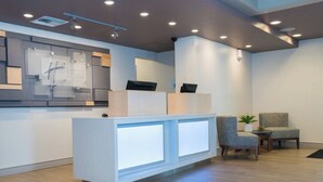 A reception area with a modern design, featuring a reception desk, seating area, and a wall-mounted information board. - Holiday Inn Express Moss Point by IHG (Moss Point)