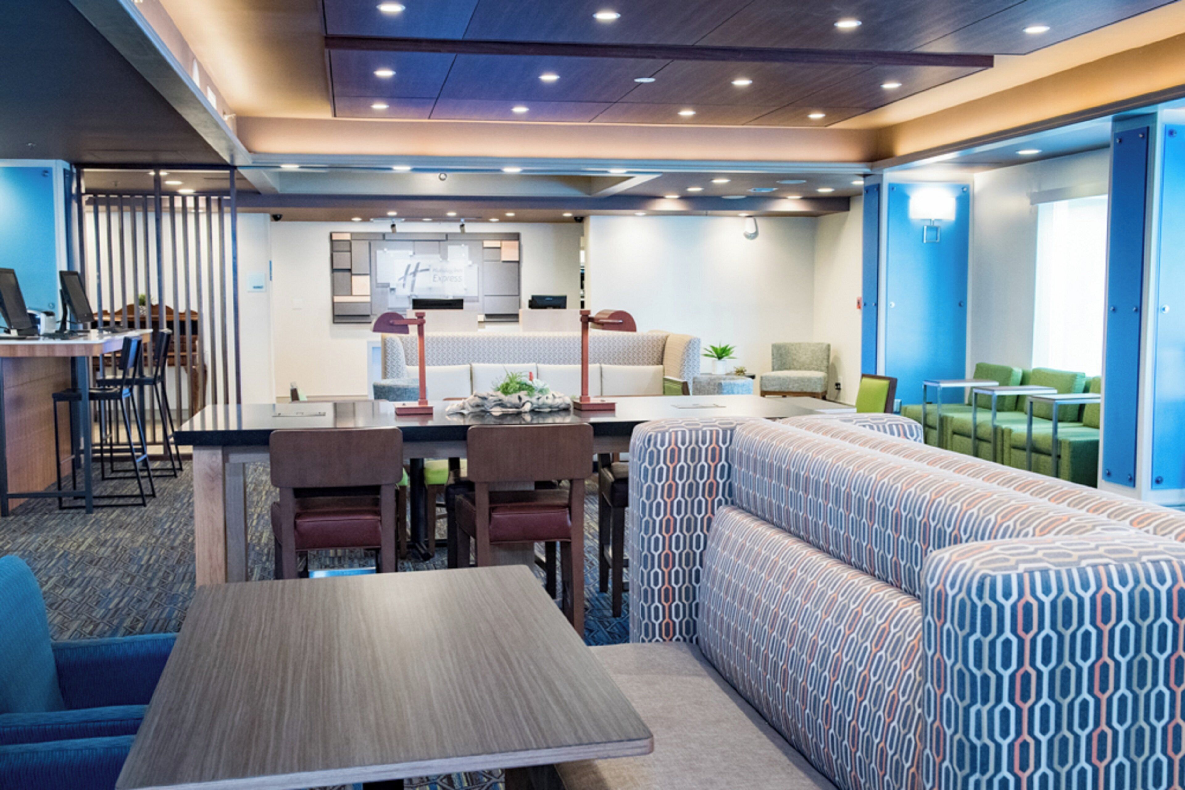 Eine moderne Hotelhalle mit einer Rezeption, einer Sitzecke und einem gemusterten Sofa.