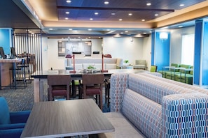 A modern hotel lobby with a reception desk, seating area, and a patterned sofa.