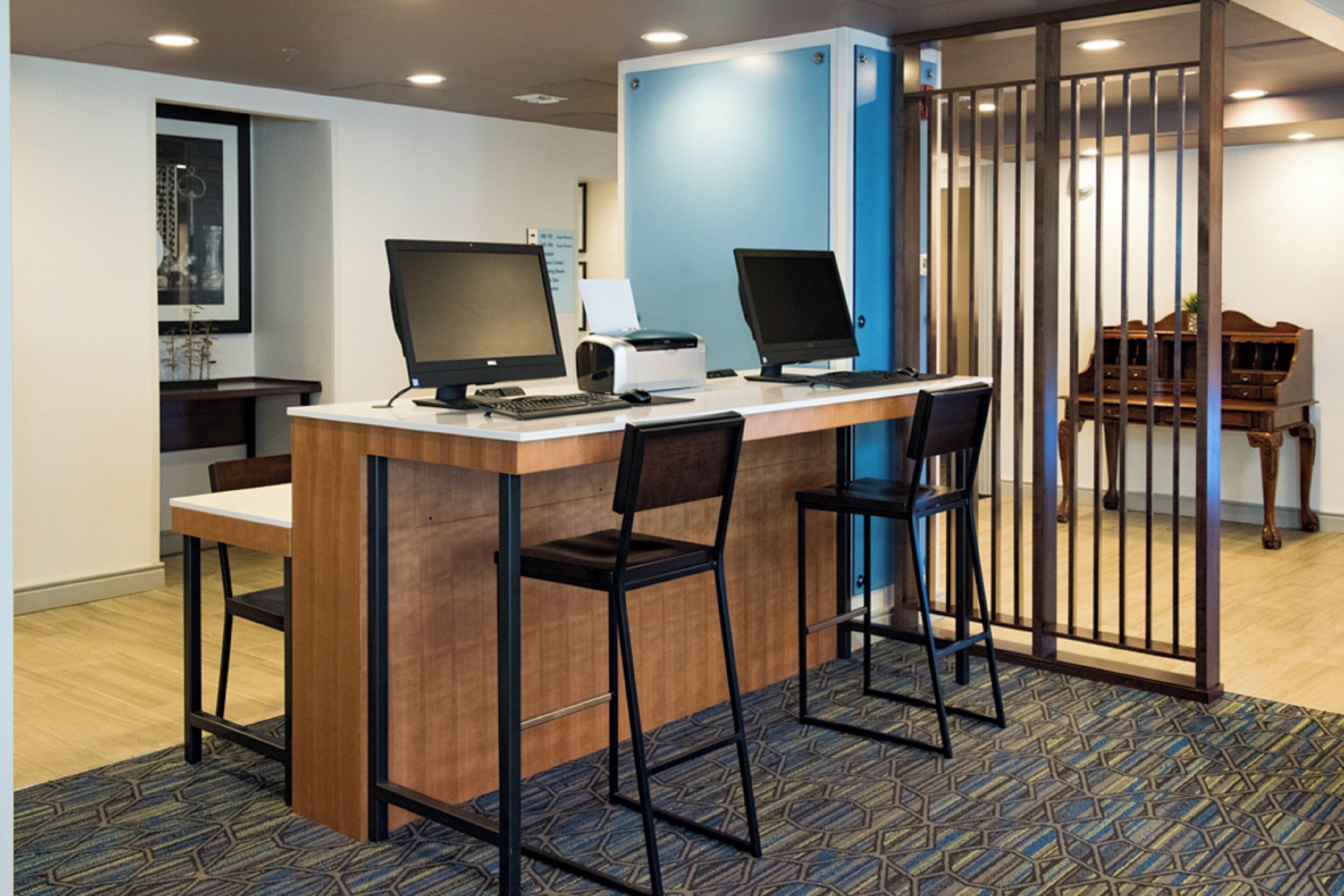 A reception desk with two computer monitors, a printer, and two chairs.