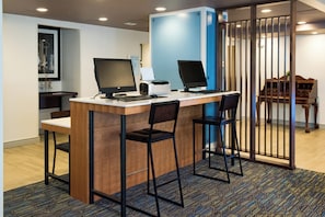 A reception desk with two computer monitors, a printer, and two chairs.