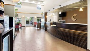 A spacious lobby with a reception desk, modern pendant lighting, and a large window providing natural light. - Comfort Suites Portland Airport (Portland)