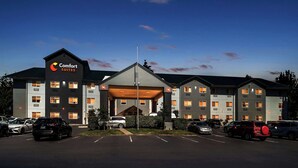 A Comfort Suites hotel with a covered entrance, multiple floors, and a parking lot. - Comfort Suites Portland Airport (Portland)