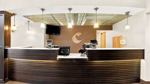 A reception desk with a crescent moon design, a flat-screen TV, and a telephone. - Comfort Suites Portland Airport (Portland)