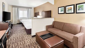 A hotel room with a bed, a sofa, a TV, a desk, and a small table. - Comfort Suites Portland Airport (Portland)