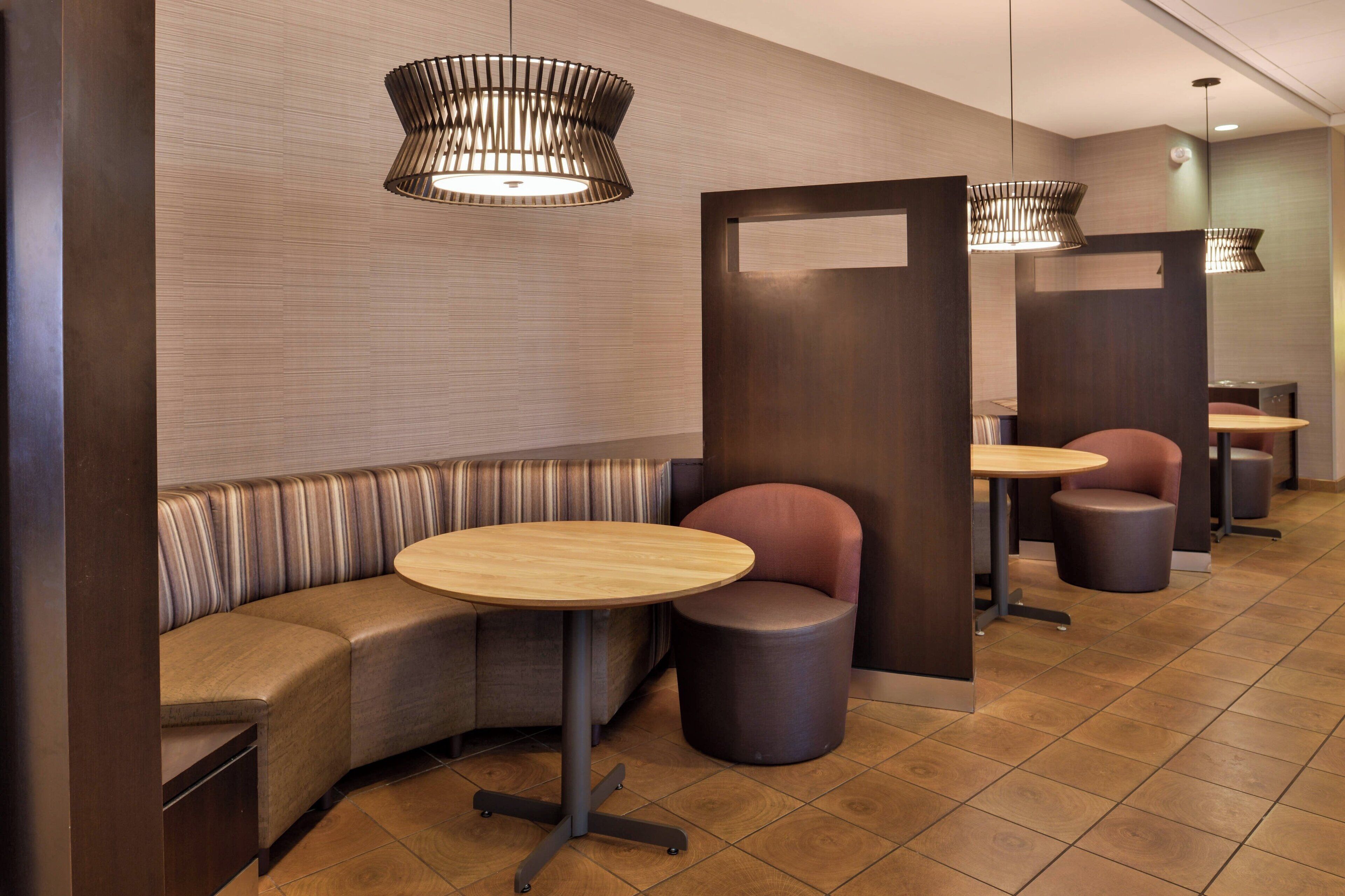 A modern restroom with a curved bench, individual stools, and pendant lighting.