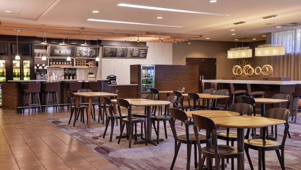Un bistró moderno con mesas y sillas de madera, una zona de bar y una pizarra de menú.