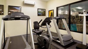 Un gimnasio con cintas de correr, elíptica y bicicleta estática.