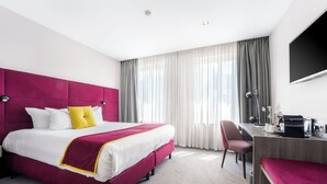 A hotel room with a large bed, a desk, a chair, and a TV. - Marivaux Hotel (Brussels)