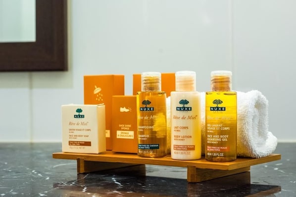 A wooden shelf with various Nuxe skincare products, including body lotion, shampoo, and face and body soap.
