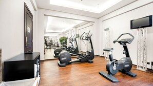 A modern gym with exercise equipment, a TV, and a large mirror. - Marivaux Hotel (Brussels)